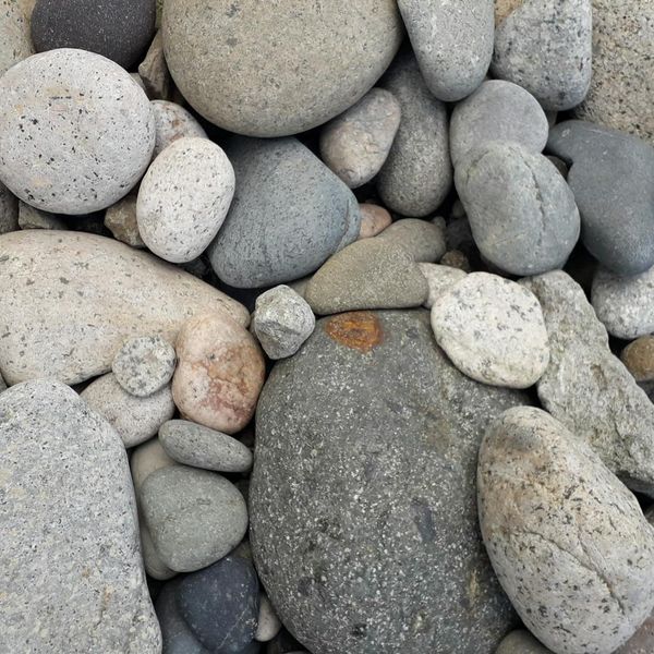 Stack of smooth stones balanced on a wooden surface in a tranquil setting.